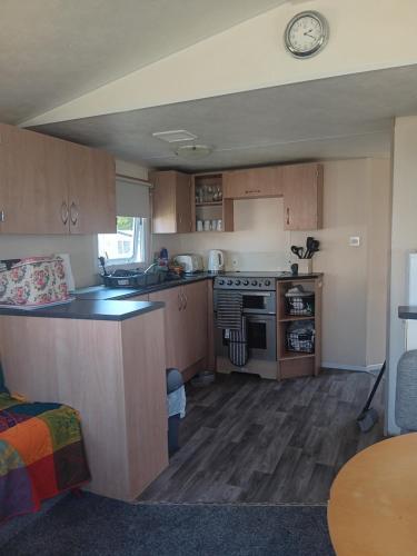a kitchen with wooden cabinets and a stove top oven at Cabana Escape in Little Clacton