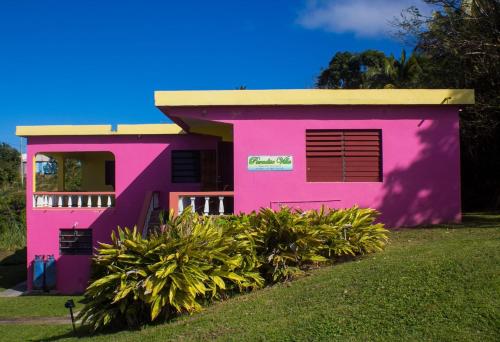 Una casa rosa con arbustos delante. en Paradise Villa, en Baker Hill