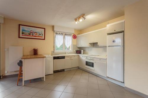- une cuisine avec des appareils électroménagers blancs et une table dans l'établissement Le Landais Wifi Terrasse Plage, à Tarnos