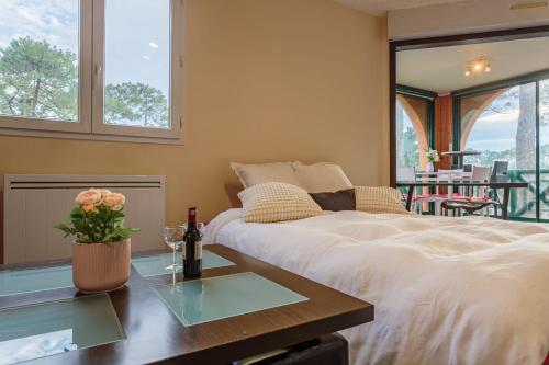 - une chambre avec un lit et une table avec des verres à vin dans l'établissement Le Landais Wifi Terrasse Plage, à Tarnos
