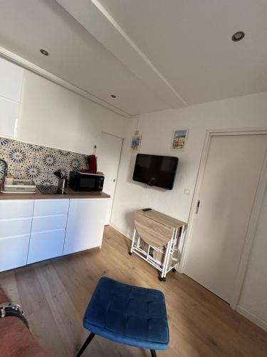 une cuisine avec un tabouret bleu et une télé au mur dans l'établissement Charmant 2 pièces sur le port avec parking gratuit et WIFI, à Sanary-sur-Mer