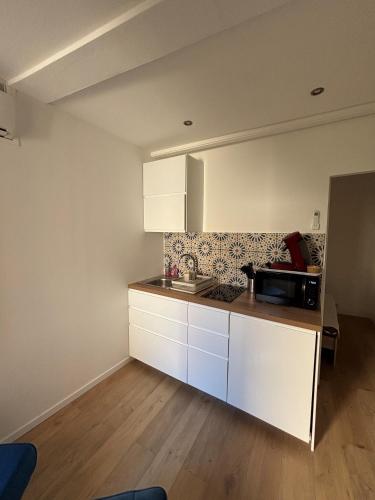 une cuisine avec des armoires blanches et un micro-ondes dans l'établissement Charmant 2 pièces sur le port avec parking gratuit et WIFI, à Sanary-sur-Mer