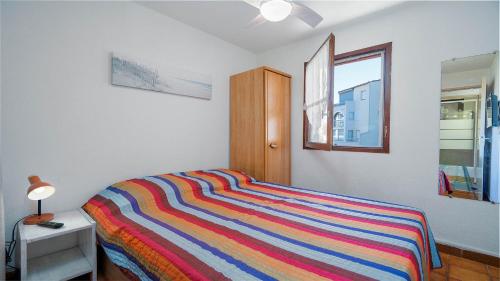 - une chambre avec un lit rayé coloré et une fenêtre dans l'établissement Aloa N113 - 2P6, au Cap d'Agde