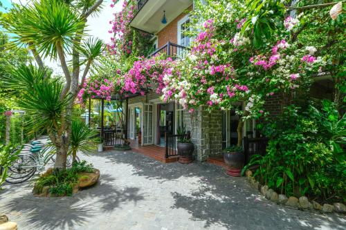 会安Ancient Garden Boutique Hoi An的旁边是一座粉红色花卉的房子