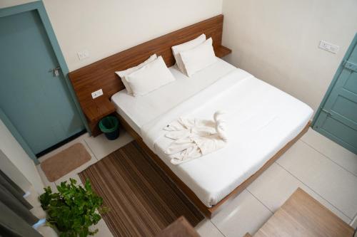 a small bedroom with a bed with white sheets at Paddle Cult Surf & Yoga in Varkala