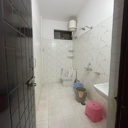 Un baño blanco con inodoro y lavabo. en Peaceful Nest Home Stay, en Rājpur