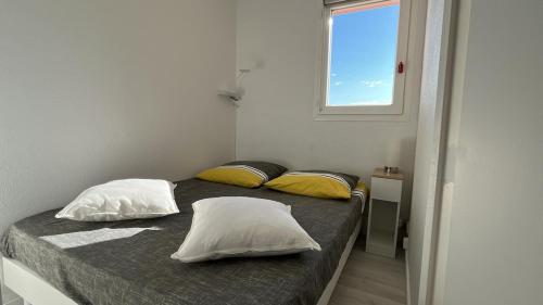 - une chambre avec un lit avec deux oreillers et une fenêtre dans l'établissement Isles Évasion-parking-100M plages-commerces, à La Londe-les-Maures