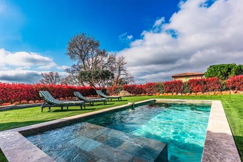 - une piscine dans une cour avec 2 chaises longues dans l'établissement Maison Sanchez - Maison Climatisée avec Piscine, à Aups