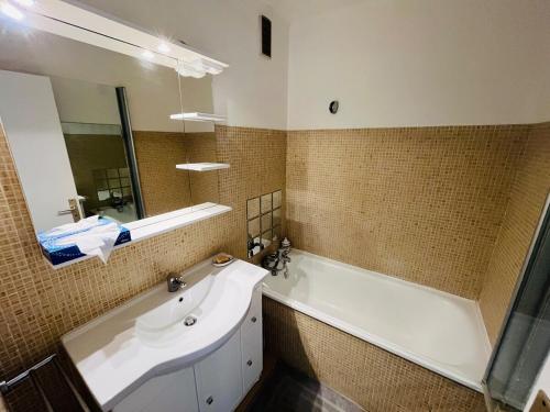 une salle de bain avec une baignoire, un lavabo et un miroir dans l'établissement T2 terrasse vue mer, à Bandol