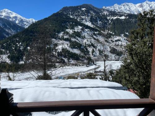 a view of a snow covered mountain from a balcony at Basho Mud Huts in Vashisht