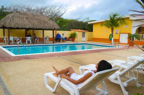 a woman laying on a chair next to a pool at Coconut Inn in Palm-Eagle Beach