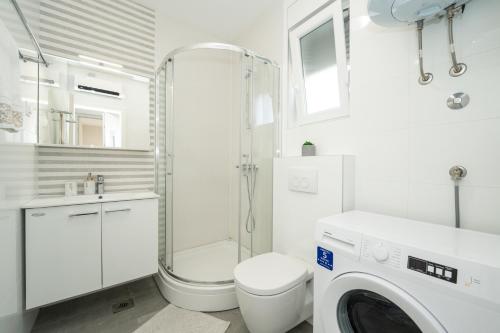 a white bathroom with a shower toilet and a washing machine at Anabella apartment - Jacuzzi & Infra Sauna in Novalja
