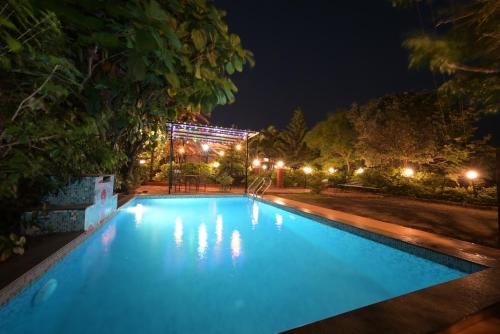 a large blue swimming pool at night with lights at Lifeline Villas - Valley View Luxurious 3bhk Surrounded by strawberry farms in Mahabaleshwar