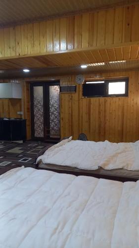 two white beds in a room with wooden walls at UYUT INN Hotel in Samarkand