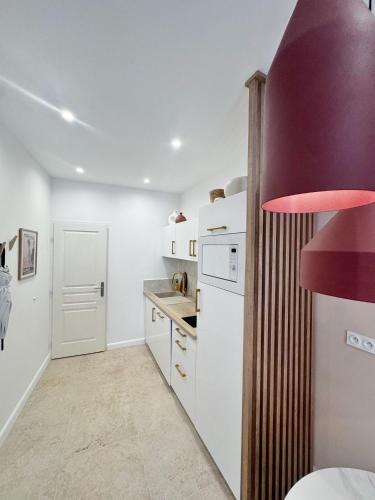 une cuisine avec des appareils blancs et une hotte rouge dans l'établissement BEACH & PALAIS - 2 Min AWAY, BALCONY, à Cannes