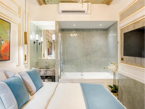 une chambre avec un lit, une baignoire et une télévision dans l'établissement Merveil - Signature Suite - Louvre - Marcel I, à Paris