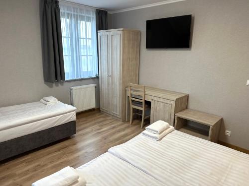 a room with two beds and a desk and a television at Karczma u Jakuba in Domaniów