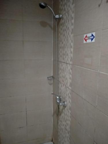 a shower in a bathroom with a sign on the wall at deKOST Madiun in Madiun