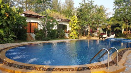 a swimming pool in front of a house at Pranburi Cabana Resort in Pran Buri