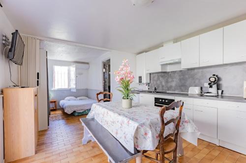 une cuisine avec des armoires blanches et une table et des chaises dans l'établissement Le Robinson - proche plage, à Marseillan