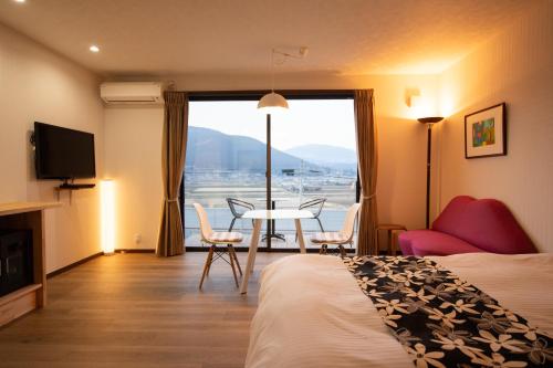 a hotel room with a bed and a table and chairs at Gran Villa Rirera Haku in Yufu