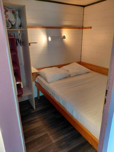 a small bed in a small room in a tiny house at Petit chalet 5 personnes in La Celle-sous-Gouzon