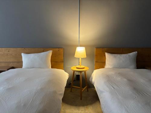 a bedroom with two beds and a table with a lamp at Hotel art rock in Takamatsu