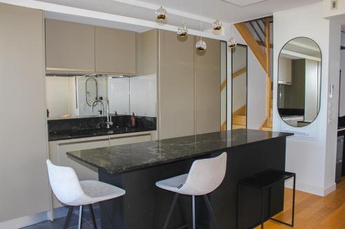 une cuisine avec un comptoir noir et deux chaises blanches dans l'établissement Spacious Duplex with Terrace City Center, à Aix-en-Provence