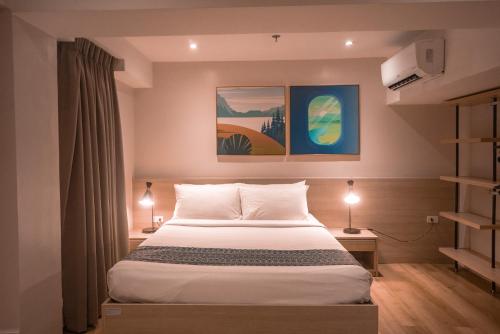 a bedroom with a bed with two lamps and two paintings at Snooze Inn & Suites in Davao City