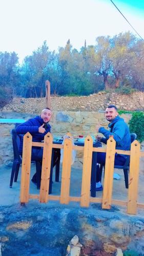 two men sitting at a picnic table on the beach at Dana Village experience hotel in Dana