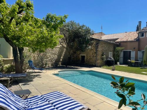 a swimming pool with two lounge chairs next to a house at Maison des Bourgades in Saint-Julien-de-Peyrolas