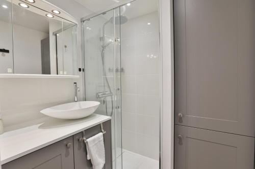 une salle de bain avec un lavabo et une douche en verre dans l'établissement Fregates - Vue mer exceptionelle au 12eme etage, à La Chaume
