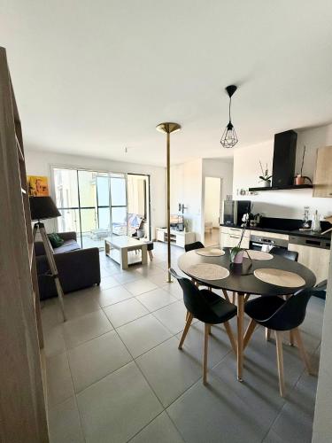 une cuisine et un salon avec une table et des chaises dans l'établissement Le bain de lumiere - Appart-Hotel, à Annecy