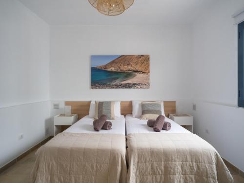 Un dormitorio con dos camas y un cuadro en la pared. en La Casa de La Graciosa, en Caleta de Sebo