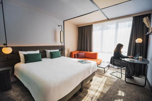 une femme assise à un bureau dans une chambre d'hôtel dans l'établissement Novotel Lens Noyelles, à Noyelles-Godault