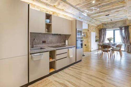 a kitchen with white cabinets and a dining room at Family Home with Jacuzzi, 3BR Countryside in Dingli in Dingli