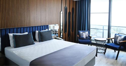 a bedroom with a large bed and two blue chairs at Elite World Resort Mersin Silifke in Silifke