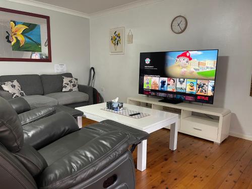a living room with a couch and a flat screen tv at Garden View Entire Self Contained Guesthouse in Engadine