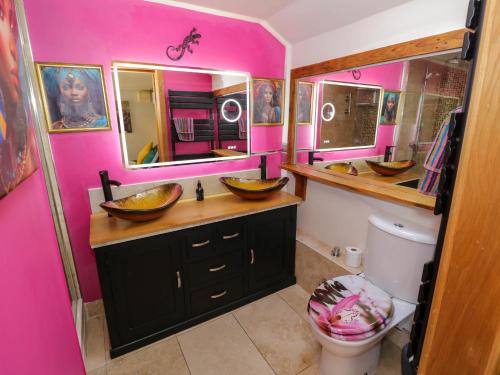 Baño con 2 lavabos y pared rosa en The Pheasant's Nest, en Welland