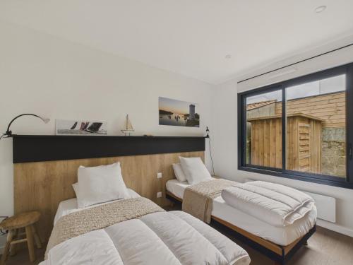 une chambre avec deux lits et une grande fenêtre dans l'établissement Jolie maison moderne - jacuzzi - terrasse pour 4, à Saint-Gilles-Croix-de-Vie