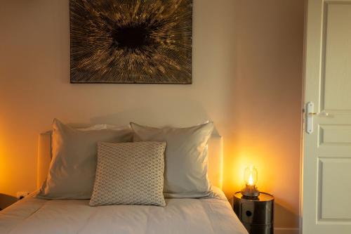 a bed with white pillows and a picture on the wall at Maison Baron - Bourgeois Residence 1h30 from Paris in Boiscommun