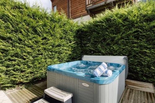 a hot tub in a backyard with bushes at Stylish 3-bed Apartment With Jacuzzi Central Mor in Morzine