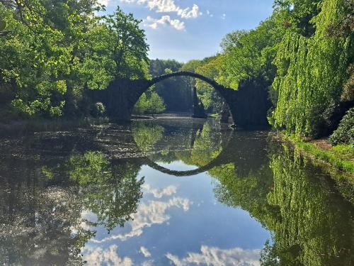 an old bridge over a river with trees and water at Ruhige Unterkunft im Erdgeschoss ,Nähe Schloss & UNESCO-Geopark, Waldeisenbahn, Natur und Kultur direkt vor der Tür in Bad Muskau