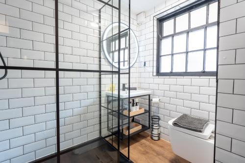 a bathroom with white tiled walls and a window at Ultra Modern Studio Apartment, in Central Exeter in Exeter