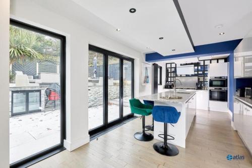 a kitchen with a counter and some chairs in it at Large NEW Detached House Woolton, Families, FREE Parking, Massage, BBQ, Play room & MORE in Woolton