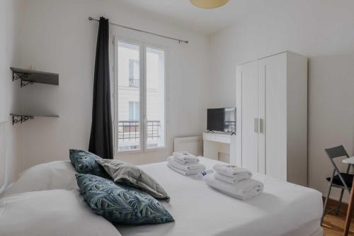 une chambre blanche avec un lit avec des serviettes dessus dans l'établissement Joli studio pour 2 personnes - Levallois-Perret, à Levallois-Perret