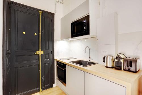 - une cuisine avec un évier et une porte noire dans l'établissement Cosy studio - 2P - Place de la Concorde, à Paris
