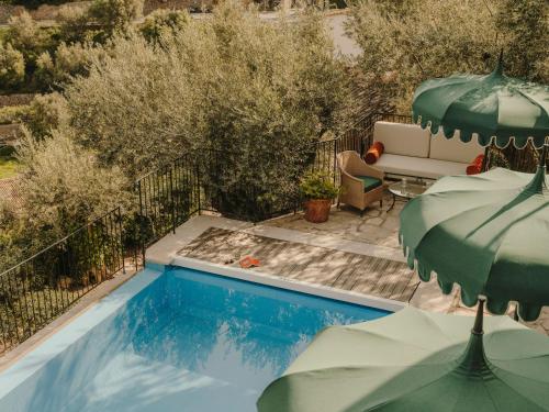 a swimming pool with a bench and an umbrella at La Residencia, A Belmond Hotel, Mallorca in Deia