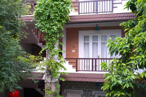 a red brick house with a balcony and trees at Ancient Garden Boutique Hoi An in Hoi An