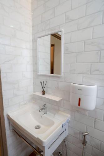 a white bathroom with a sink and a mirror at Ongsa Poolvilla At Udonthani in Ban Dong Saphang